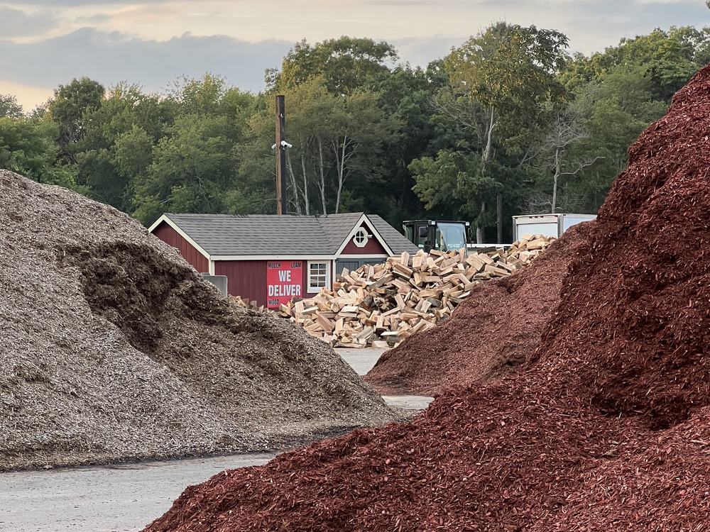 Piles of mulch, stone and firewood in front of the red barn at the Mulch N' More yard on Route 3 in Exeter, Rhode Island