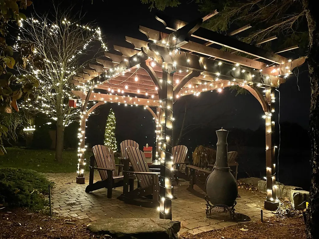 Backyard pergola wrapped in warm white holiday lights