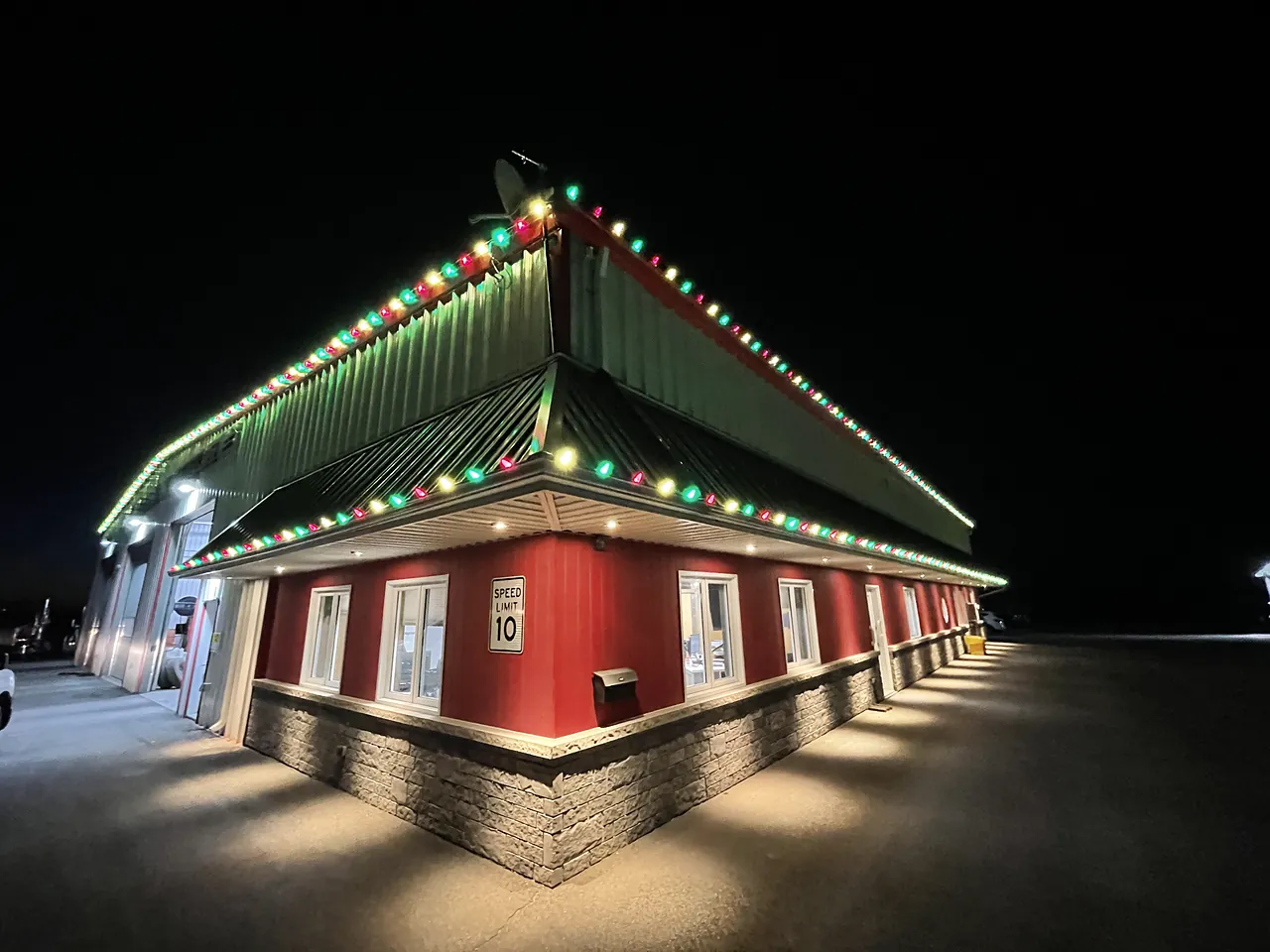 Commercial building with red, green and white holiday lights along the roofline